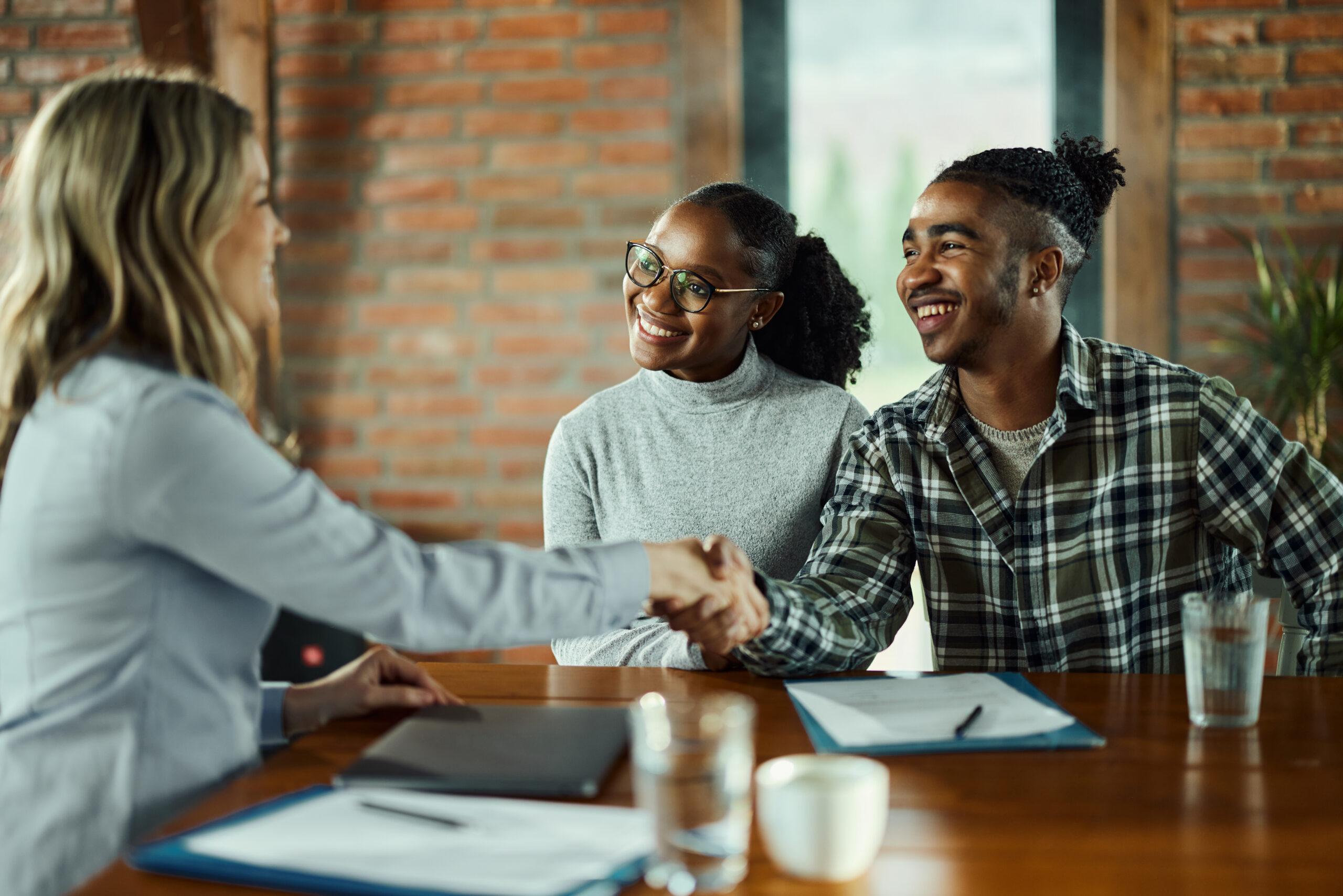 Happy real estate agent came to a successful agreement with a couple during a meeting in the office.