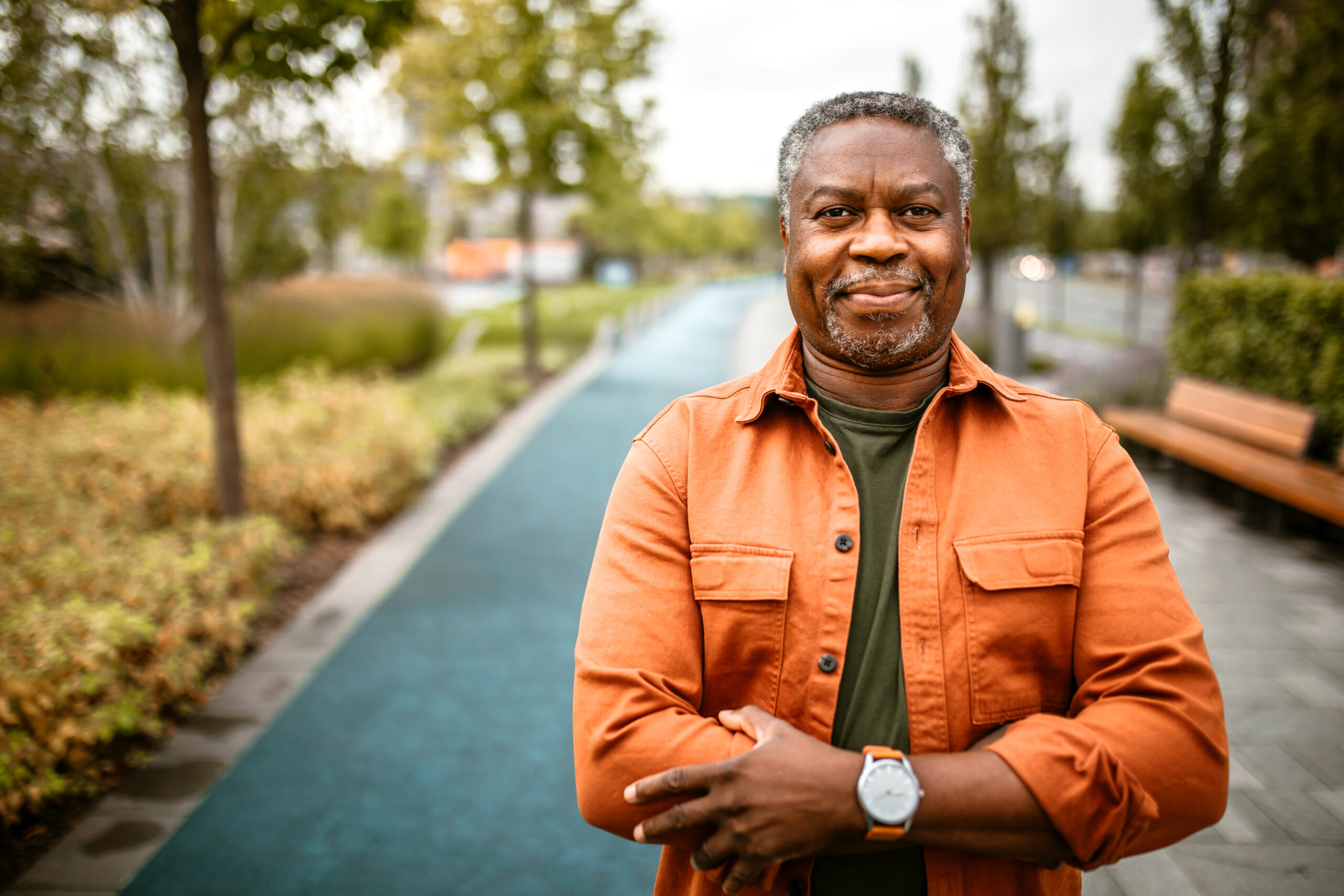 senior black man with grey hair, standing on the street, looking at camera.