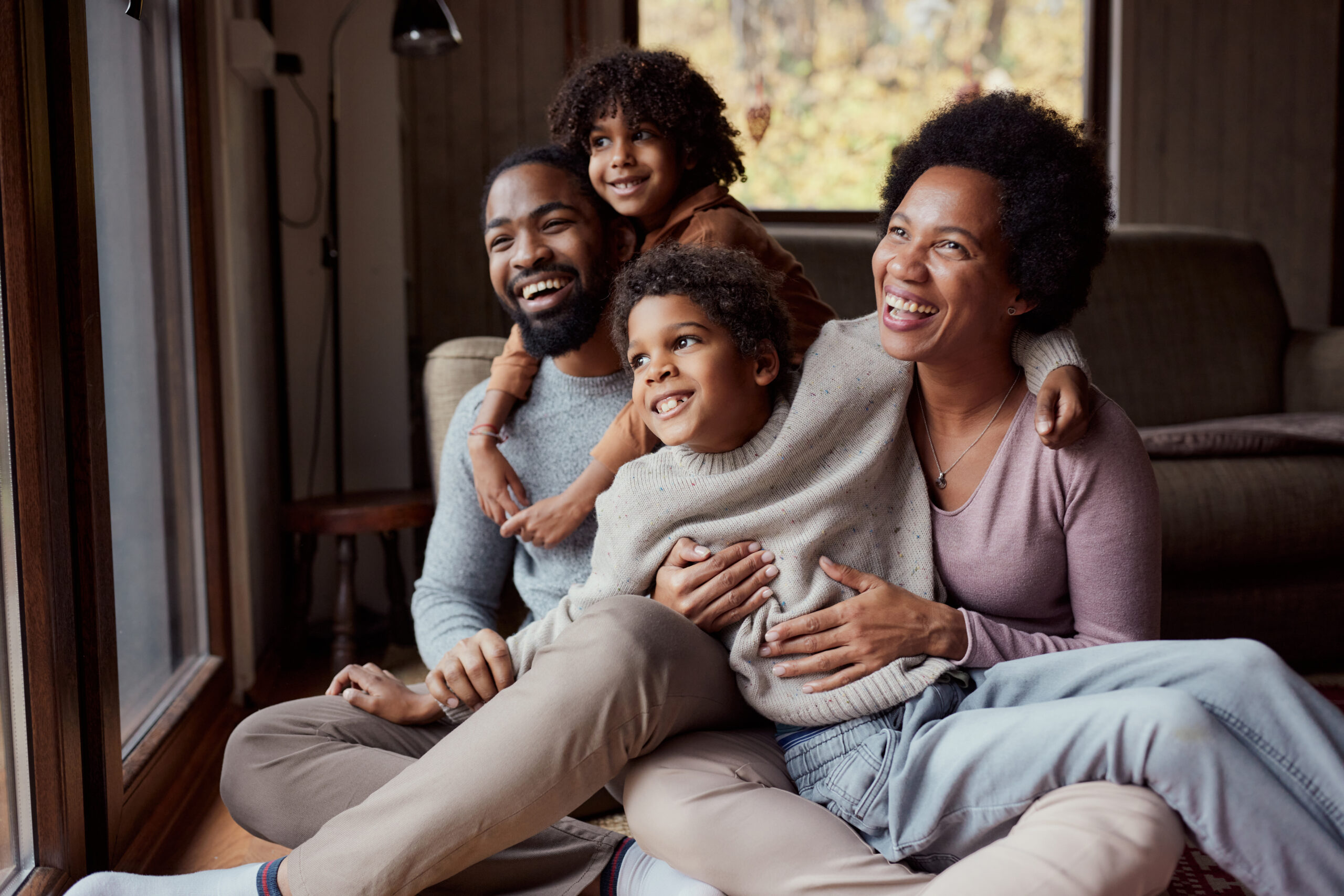 Happy African American parents and their small kids spending time together in the living room.